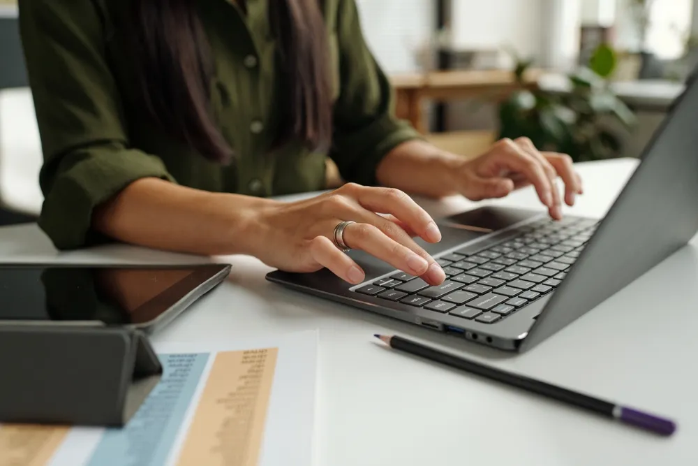 Woman typing on a computer while reviewing a financial statement.