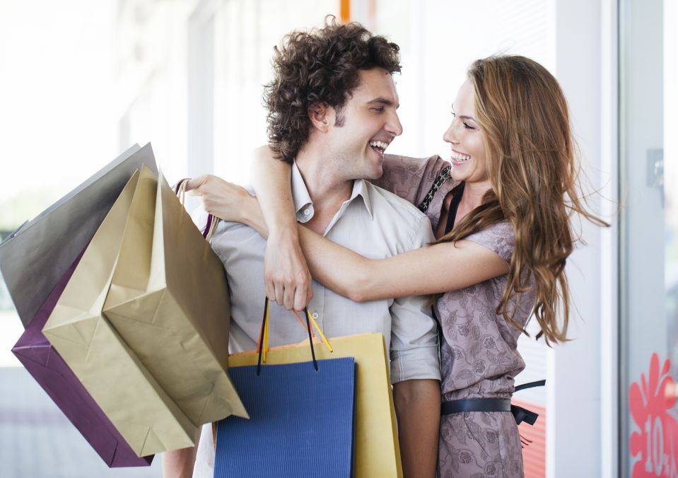Two people smiling and holding shopping bags after a shopping trip