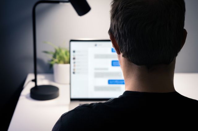 Man sitting at a desk while messaging on a computer.