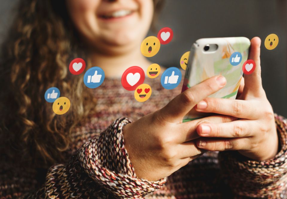 Young woman browsing social media on her phone while trying to spot common social media scams.