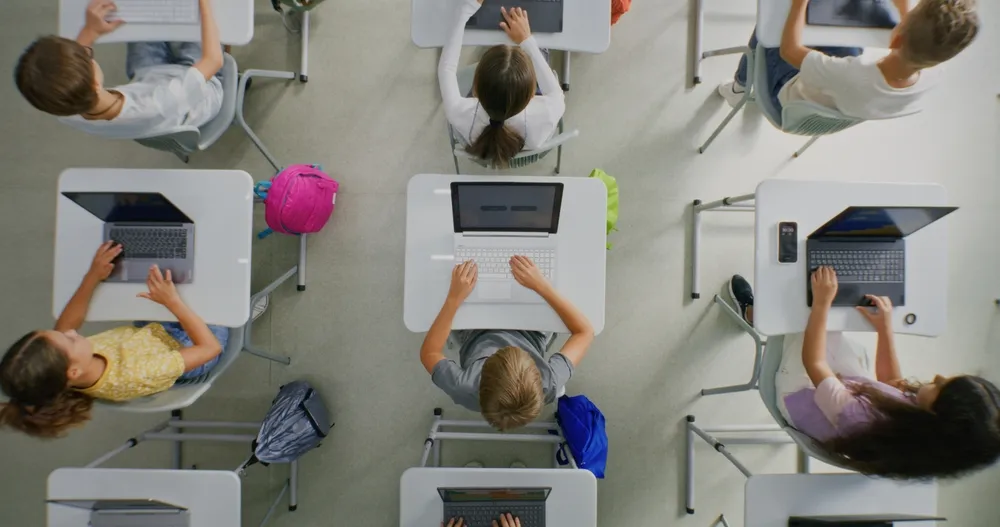 Young kids in a classroom learning how to be digitally literate while being online.
