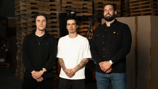 Three founders of Les Marchands standing together in the ice distribution warehouse