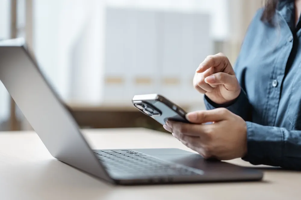 A person sending an e-Transfer on their phone while being cautious of e-Transfer scams.