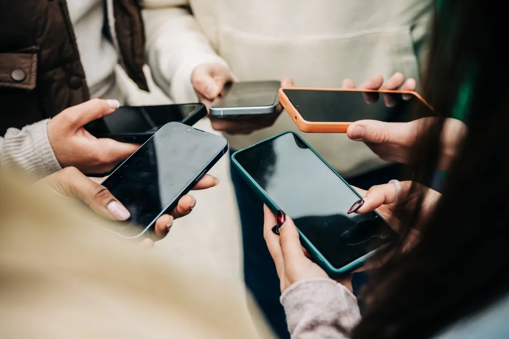 People's hands holding mobile phones in a circle, leaving behind a digital footprint while online.
