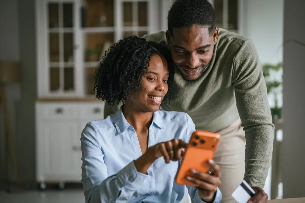 A man and a woman staying alert of scams while online shopping on their phone.