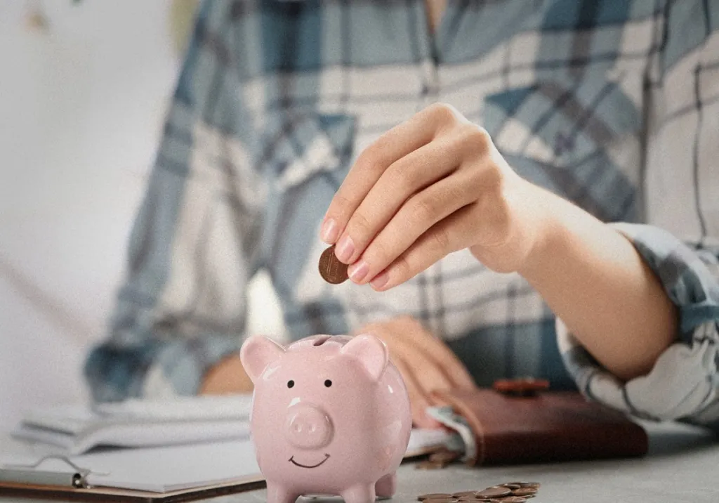 Man putting coin into piggy bank.