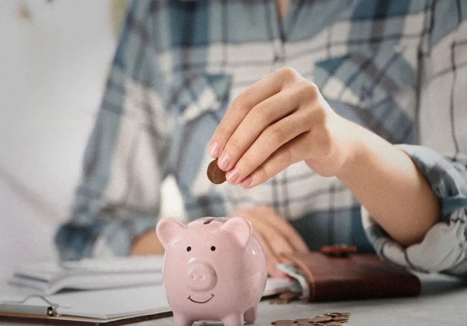 Man putting coin into piggy bank.