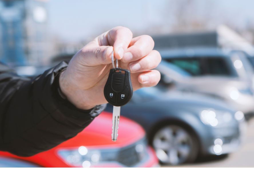 Main d'homme tenant une clé d'auto sur fond de stationnement flou