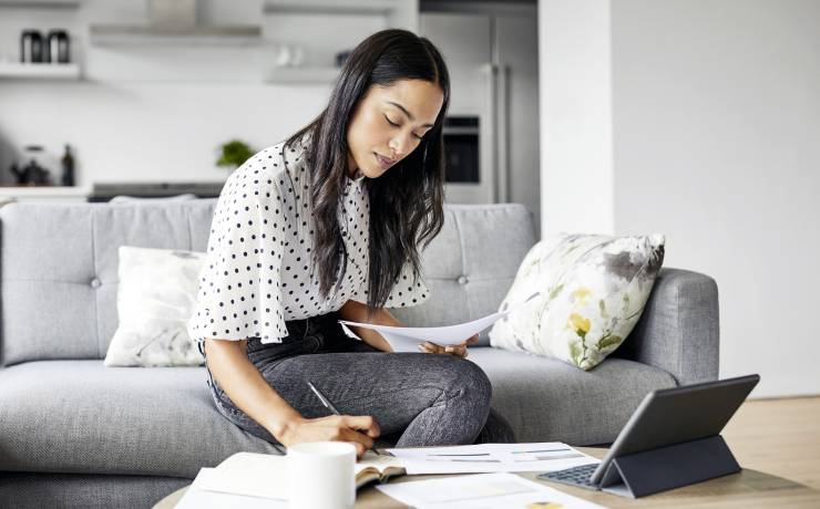 Une investisseuse consulte des documents dans son salon.