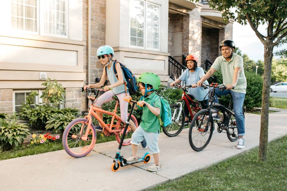 Père et trois enfants se promènent dans leur quartier à vélo et en scooter