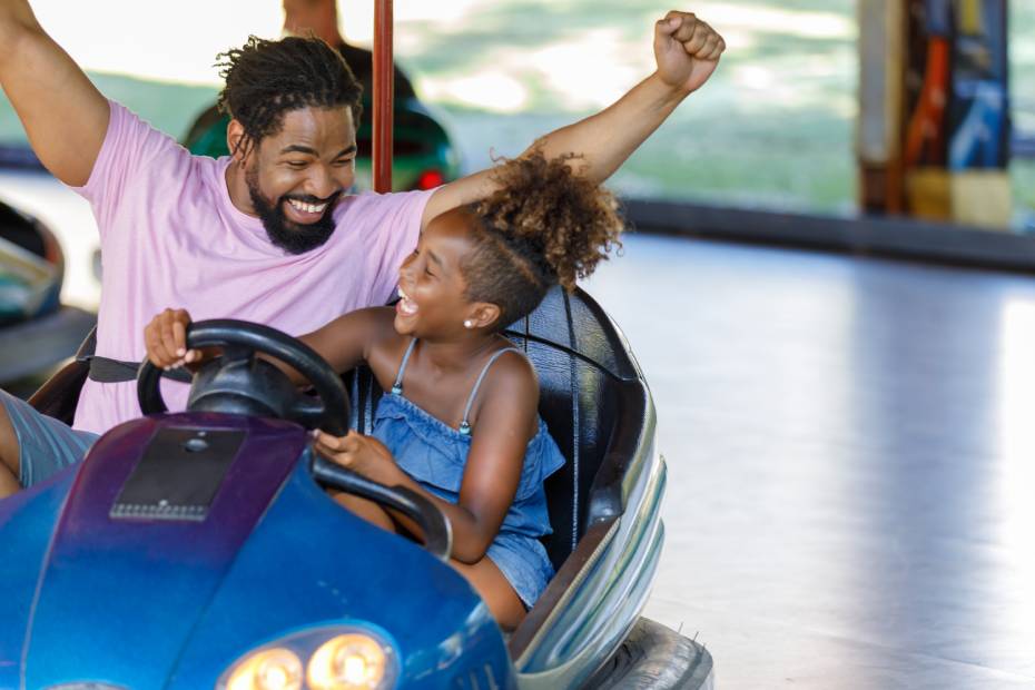 Un jeune père et sa fille s'amusent à bord d'une auto tamponneuse dans un parc d'attractions