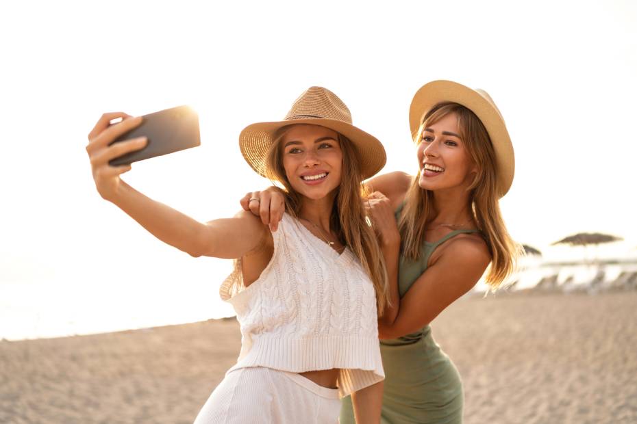 Deux filles prennent un égoportrait avec leur téléphone mobile à la plage.
