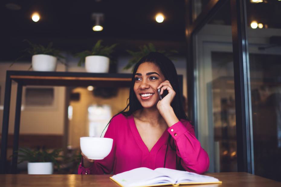 ne jeune femme souriante avec du café sur son téléphone