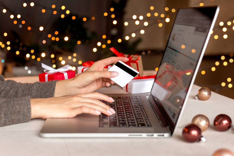 les mains d'une femme tenant une carte de crédit, faisant du shopping sur un ordinateur portable.