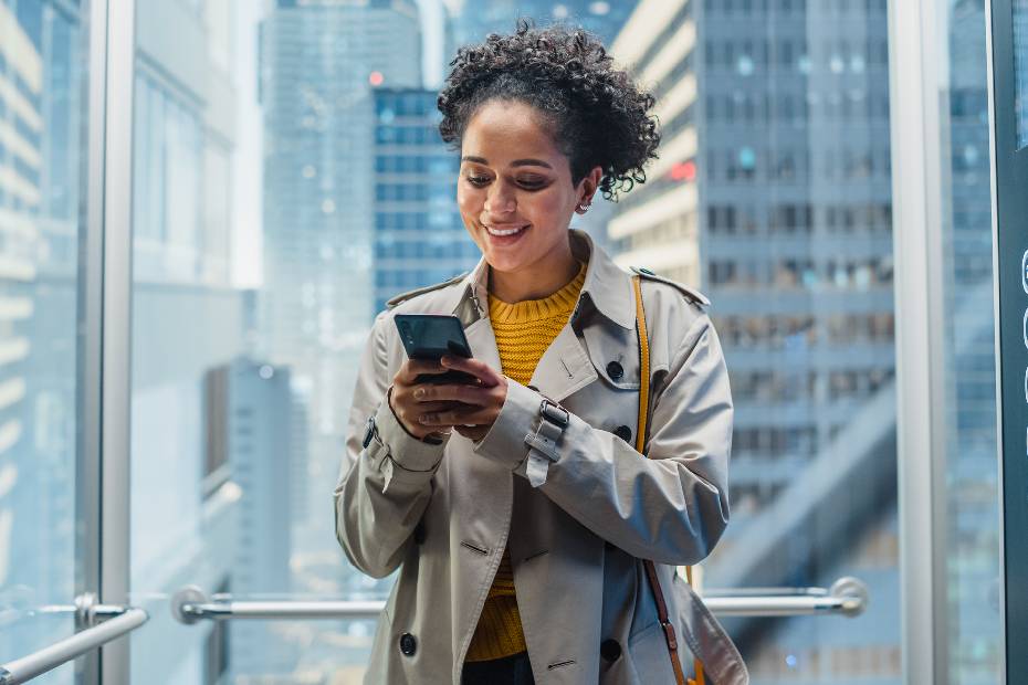 Une femme regarde son portable dans un ascenseur.