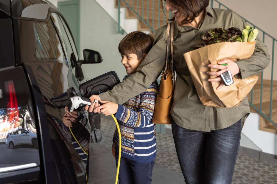Un parent en compagnie d’un enfant recharge son véhicule électrique à domicile