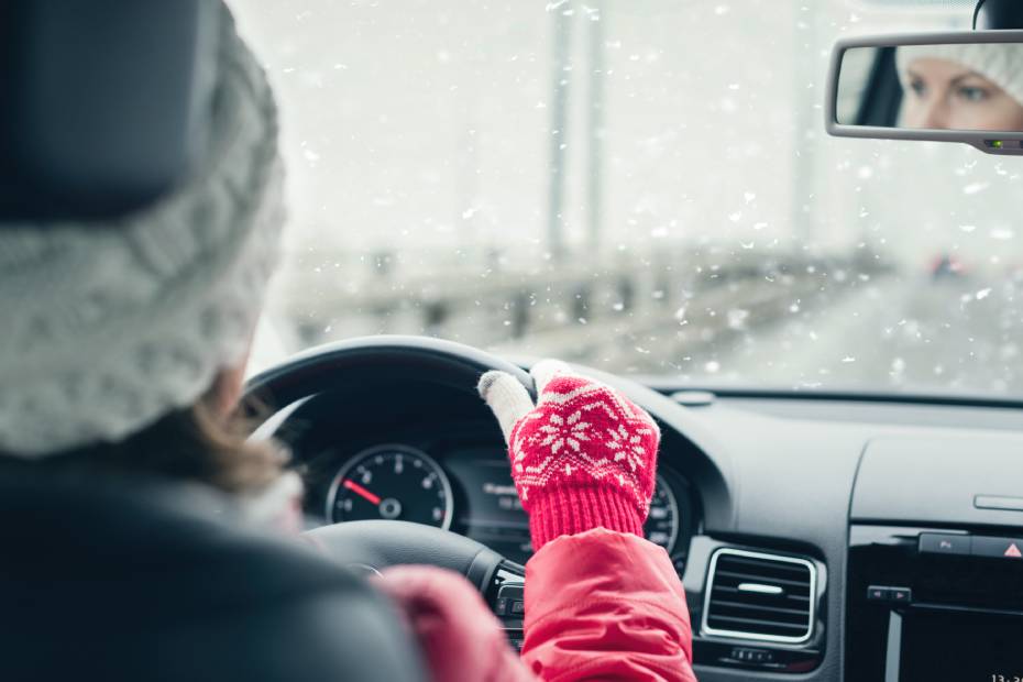 Femme portant un chapeau et des gants de laine se déplaçant en VE tandis qu’il neige à l’extérieur