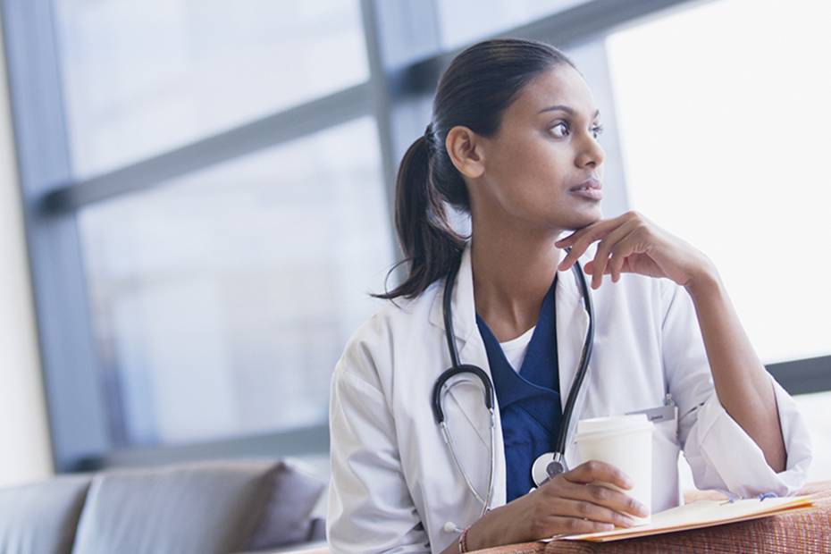 Image d'une jeune médecin regardant pensivement par la fenêtre.