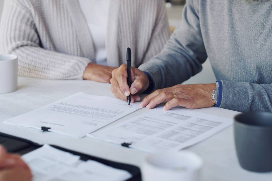 Image d'un couple signant un document devant un conseiller juridique.