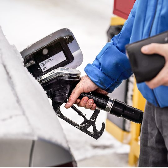 Homme tenant une buse de carburant, remplissant le réservoir d'essence d'une voiture diesel recouverte de neige