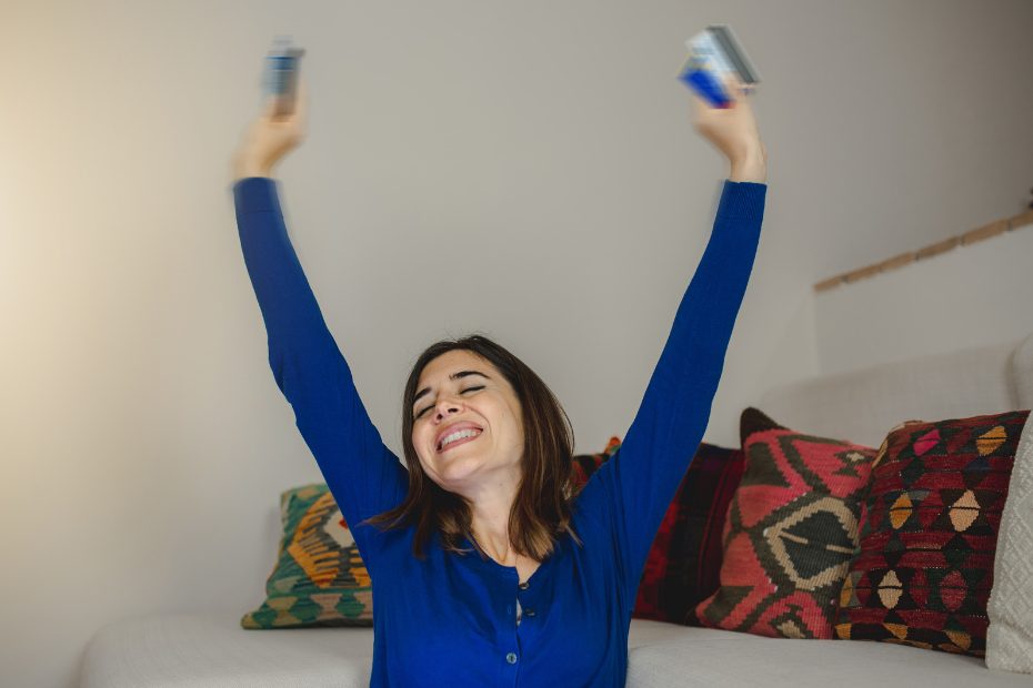 Femme levant joyeusement les bras en l'air, cartes de crédit en main