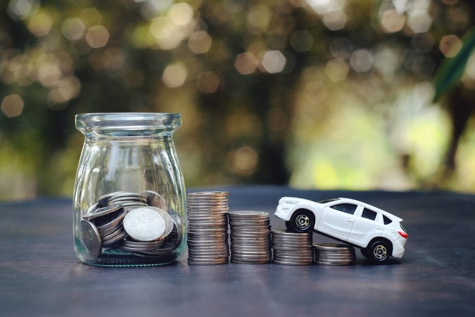 Rangée de piles de pièces de monnaie sur une table et voiture jouet gravissant ces piles