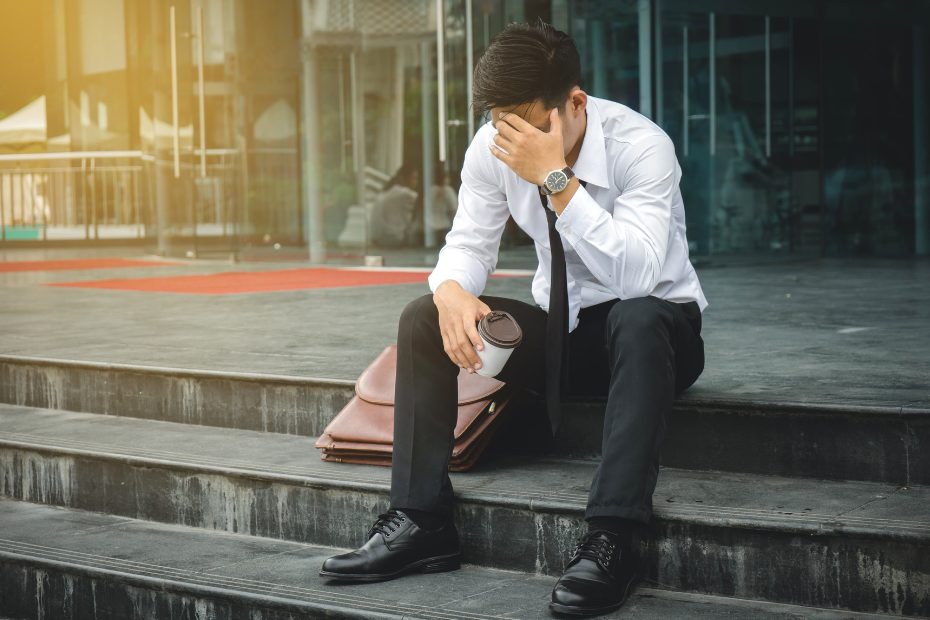 Homme d'affaires au chômage, stressé, assis sur des marches devant son bureau