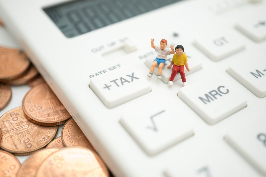 Figurines miniatures de deux enfants assis sur une calculatrice grandeur nature.