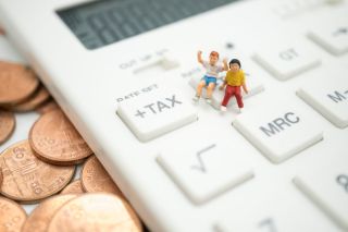 Figurines miniatures de deux enfants assis sur une calculatrice grandeur nature.