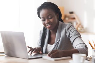 Une entrepreneure noire examine ses finances sur un ordinateur.