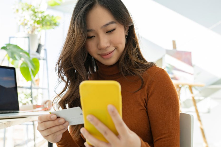 Jeune femme asiatique magasinant en ligne avec son téléphone mobile