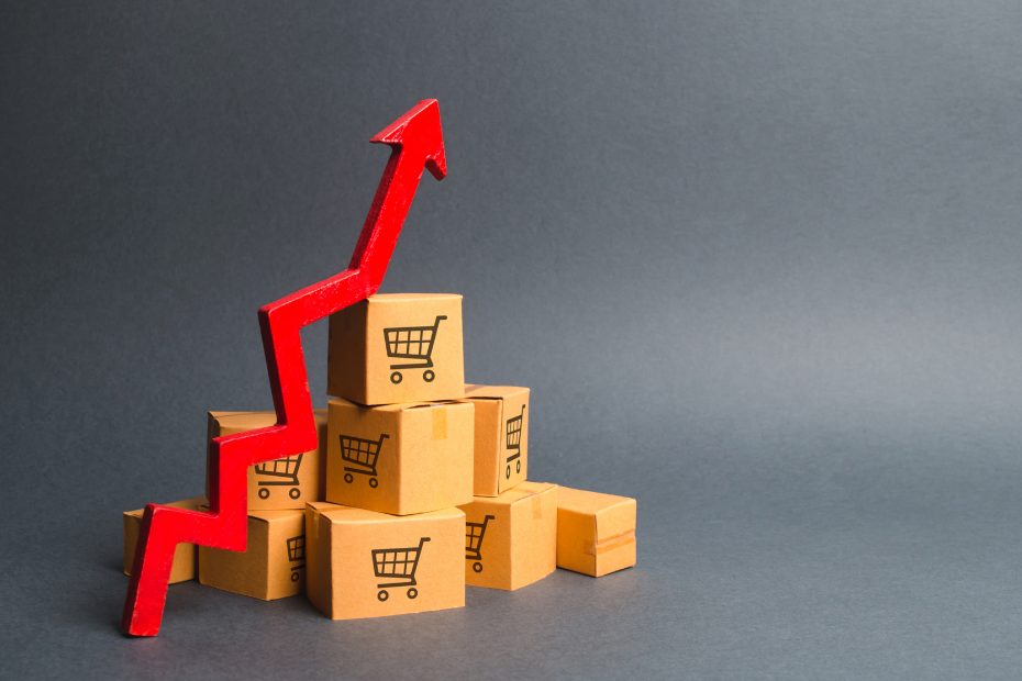 Pile de boîtes de carton de magasins et flèche rouge ascendante représentant la hausse des taux d'intérêt.