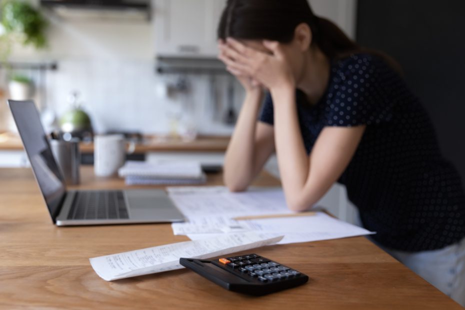 Femme stressée regardant son ordinateur et ses factures à la table de la cuisine