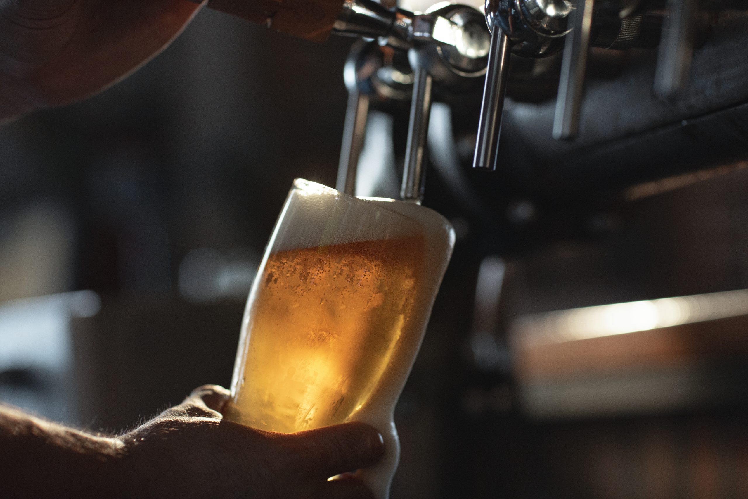 une personne versant un verre de bière du robinet.