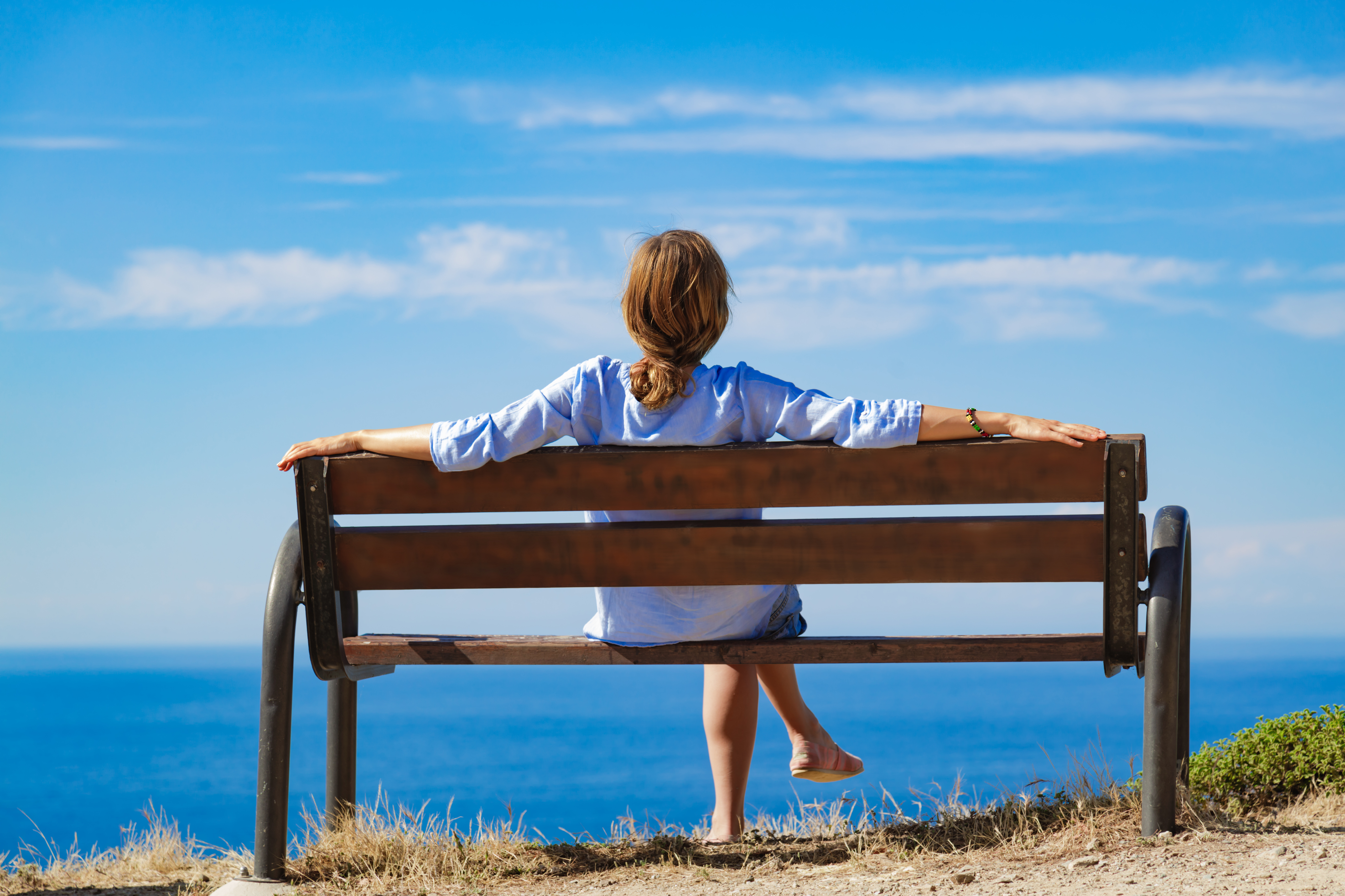Femme assise sur un banc avec vue sur l'océan