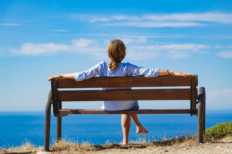 Femme assise sur un banc avec vue sur l'océan