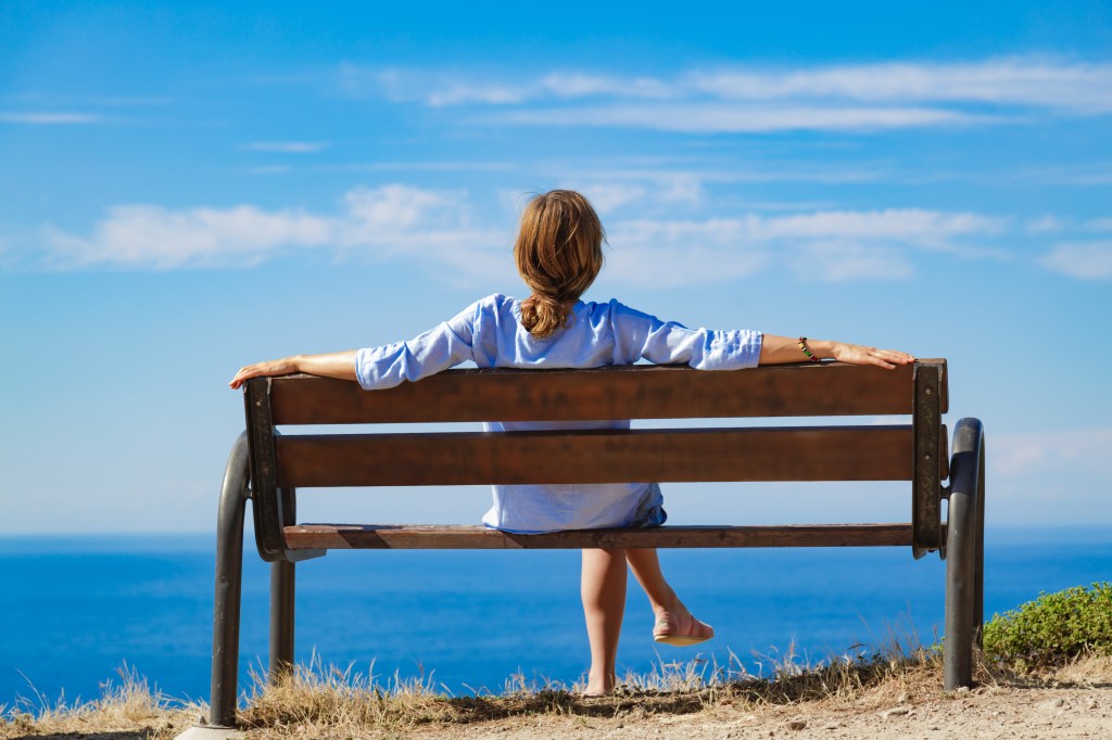 Femme assise sur un banc avec vue sur l'océan