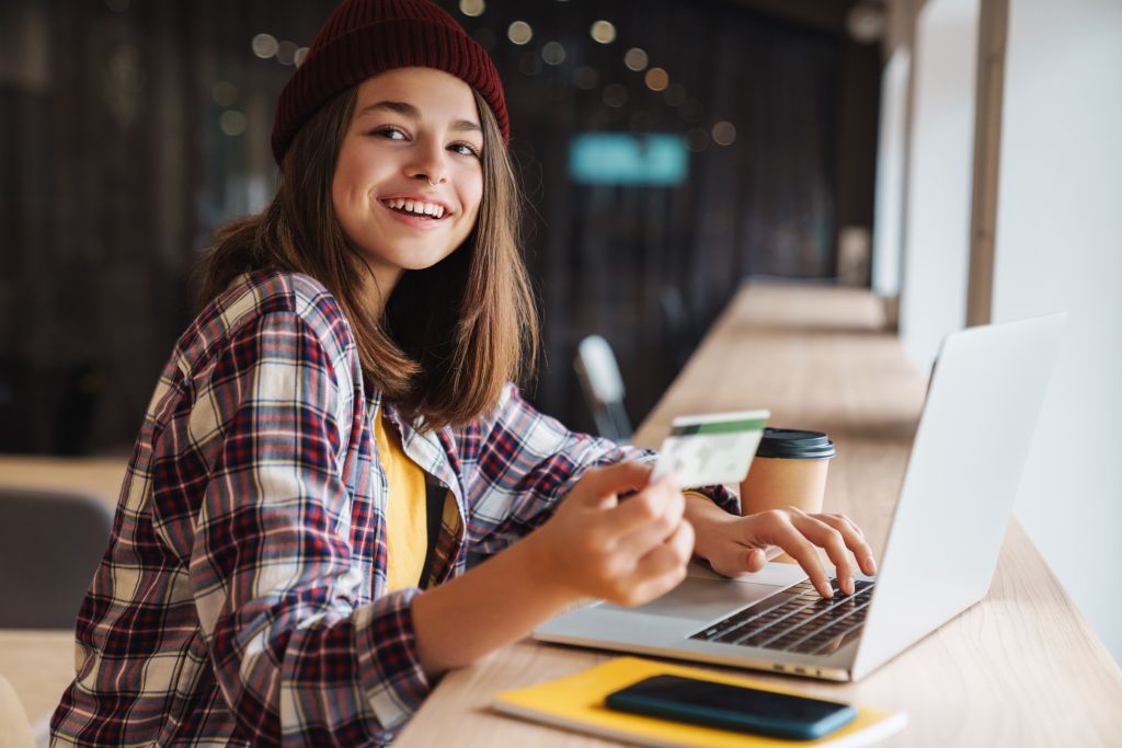 Un jeune étudiant sur un ordinateur portable avec une carte de crédit