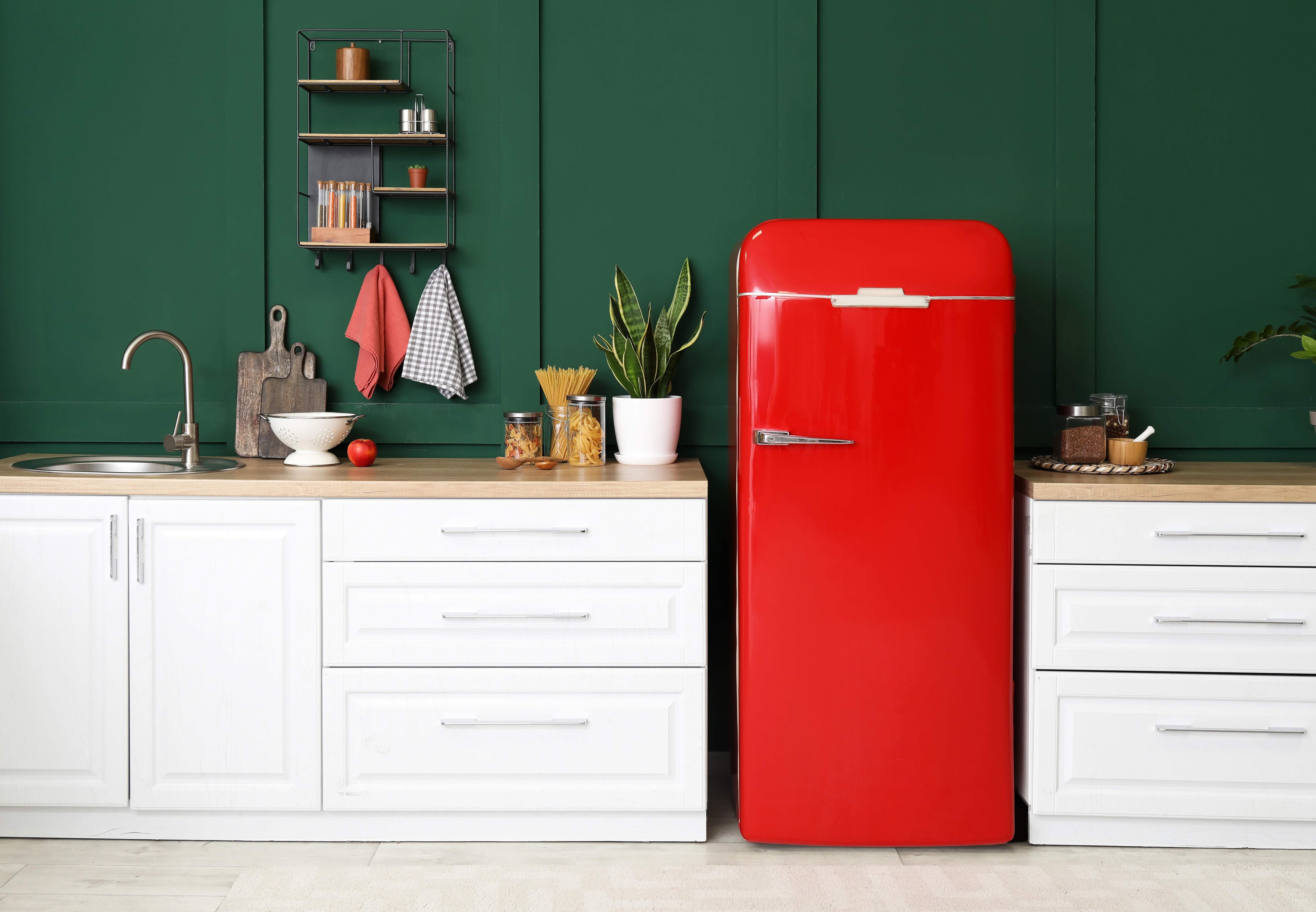 Une cuisine moderne et propre avec un réfrigérateur rouge contre un mur vert foncé