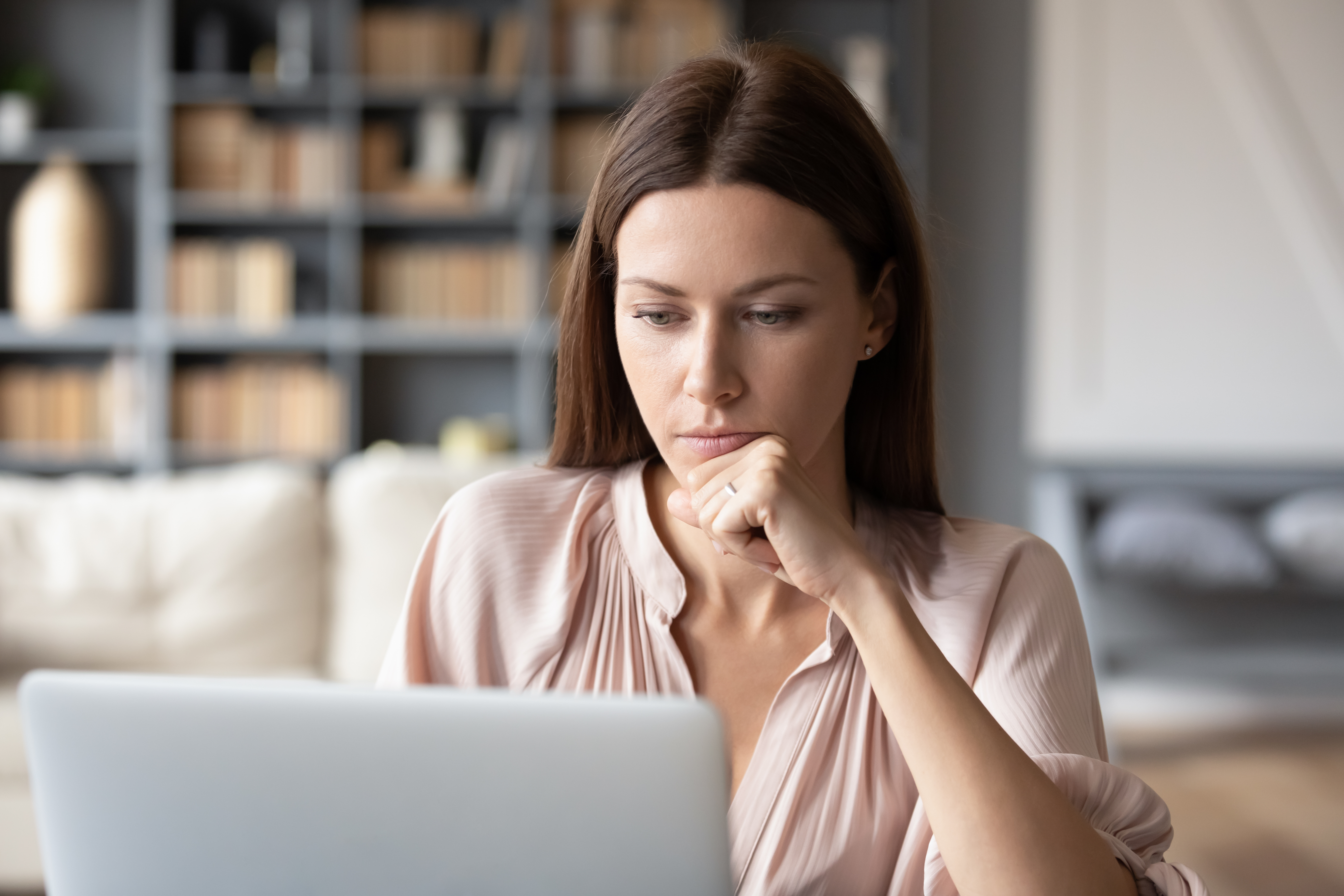 Femme regardant l'écran de son ordinateur portable, réfléchissant à des questions pressantes.