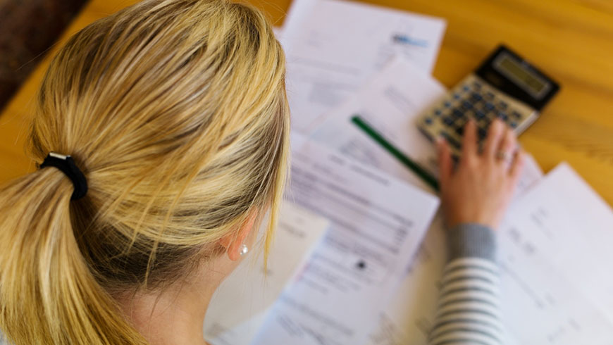 Vue de dos d’une femme assise à un bureau en train d’examiner des dépenses