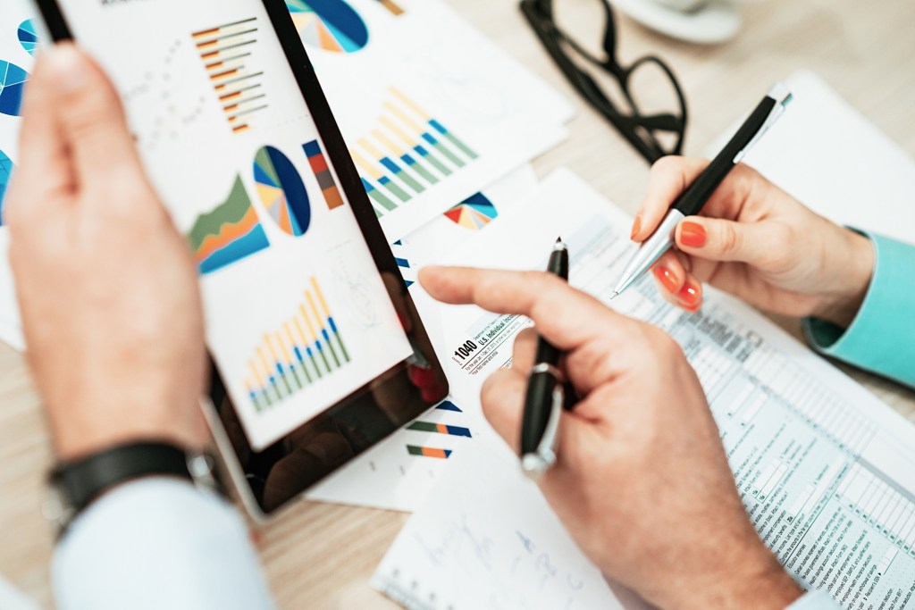 Deux professionnels en fonction, une jeune femme et un homme, en tenue formelle, s'occupant de la finance, des questions financières, des investissements et de l'analyse de marché. Image prise d'en haut : image aérienne, représentant le travail d'équipe et la collaboration, le brainstorming et le travail innovant progressif.