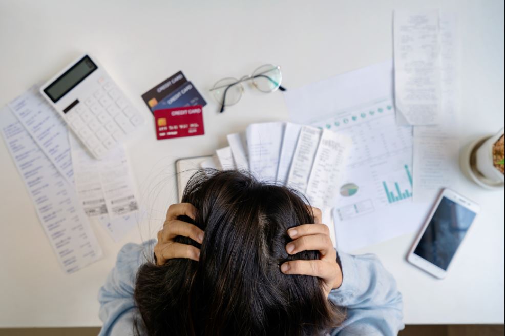 Jeune femme tendue, assise à son bureau, devant des factures