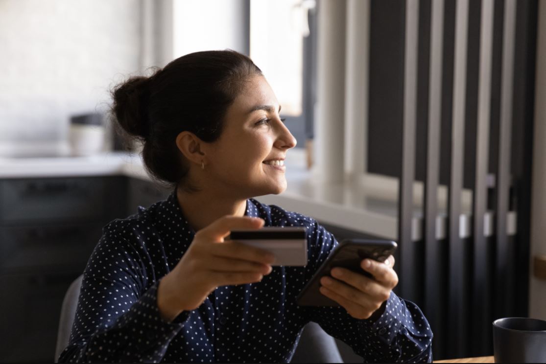 Souriante jeune femme indienne faisant du shopping en ligne