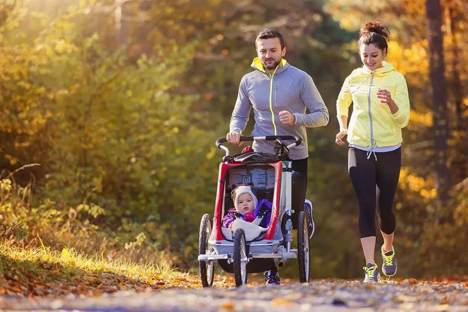 Jeune couple faisant du jogging avec son enfant dans la poussette