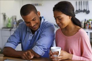 Un jeune couple consultant ses services bancaires en prenant un café.
