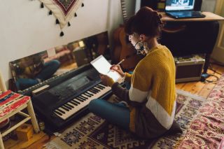 Femme hippie assise sur le sol et utilisant une tablette pour créer une nouvelle musique