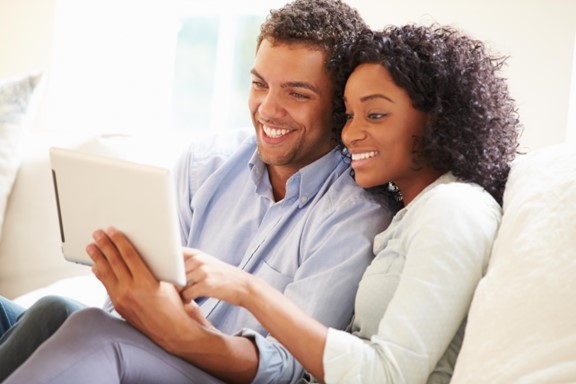 Jeune couple qui discute de finances sur un sofa, une tablette à la main