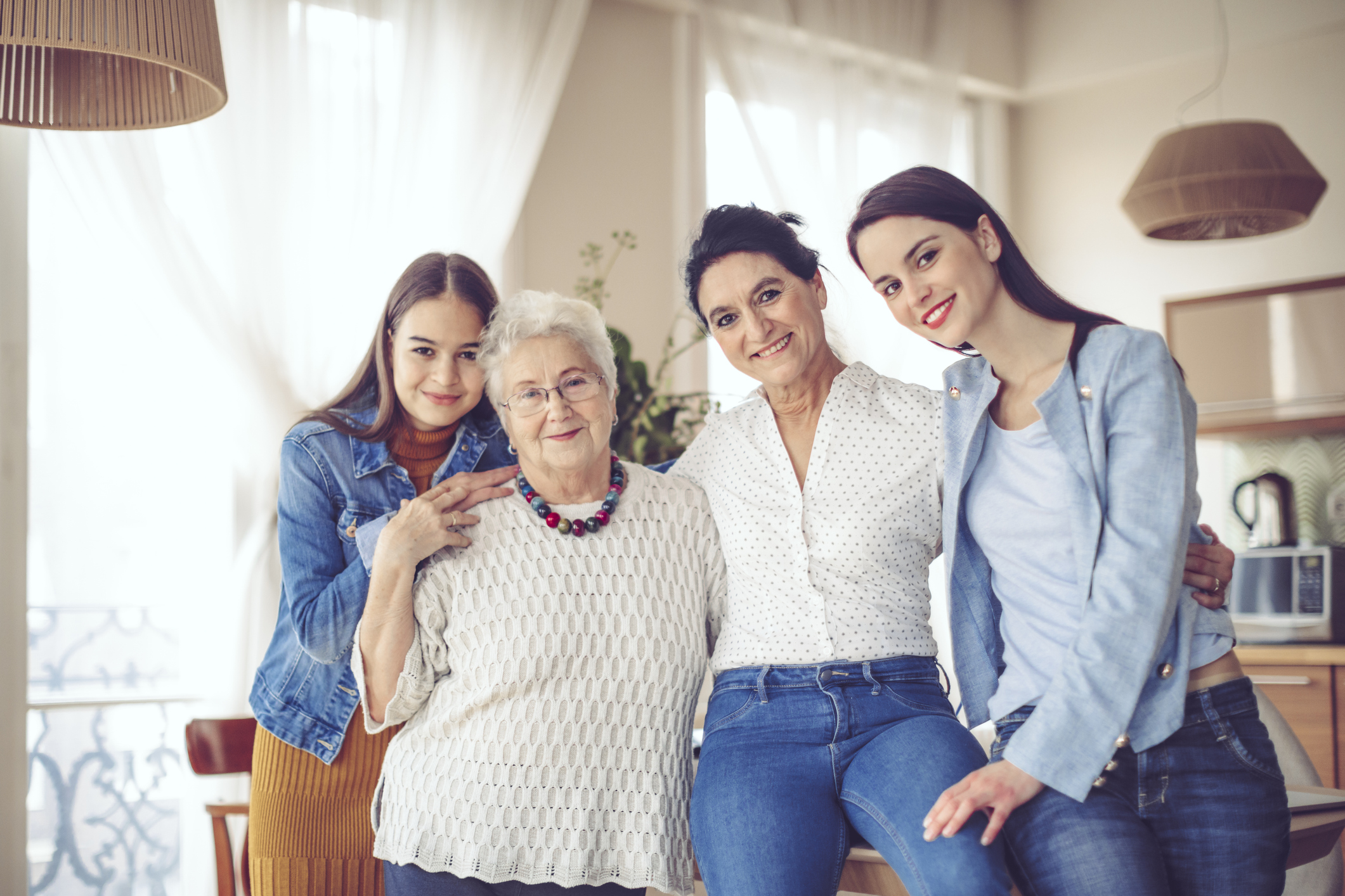 Famille multigénérationnelle heureuse de femmes posant dans leur salon.