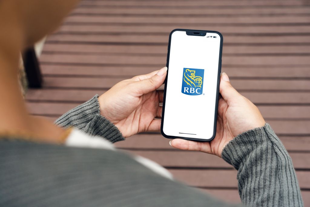 Fille dans le parc tenant un smartphone avec l'application de la Banque Royale du Canada à l'écran.